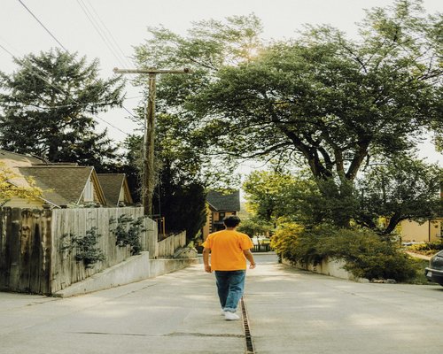 A person walking gently through a tree-lined street in the neighborhood